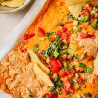 A baking dish with chili cheese dip and tortilla chips.