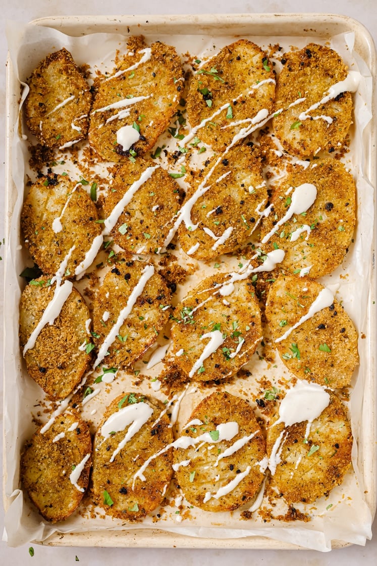 Garnished parmesan crusted potatoes on a baking sheet.