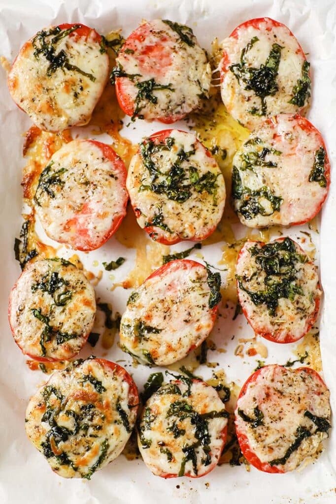 A baking sheet filled with baked tomatoes and basil.