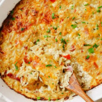 Hash brown breakfast casserole on a baking dish with a wooden spoon.