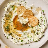 Whipped feta with honey dip and crackers on a plate.