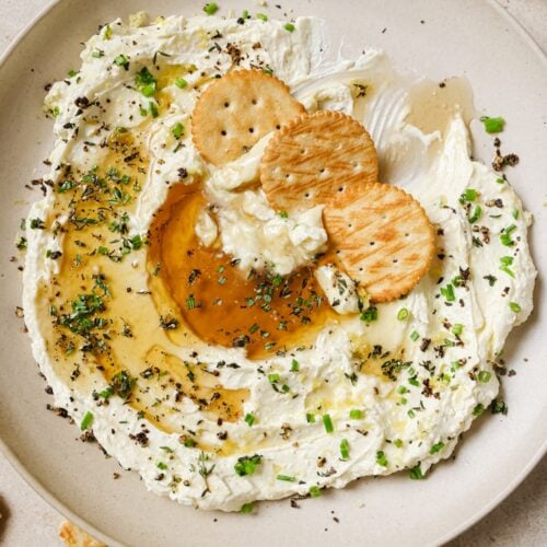 Whipped feta with honey dip and crackers on a plate.