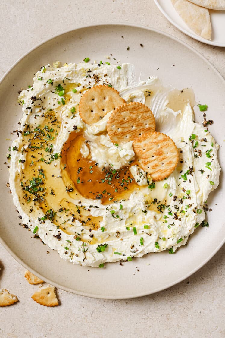 Whipped feta with honey dip and crackers on a plate.