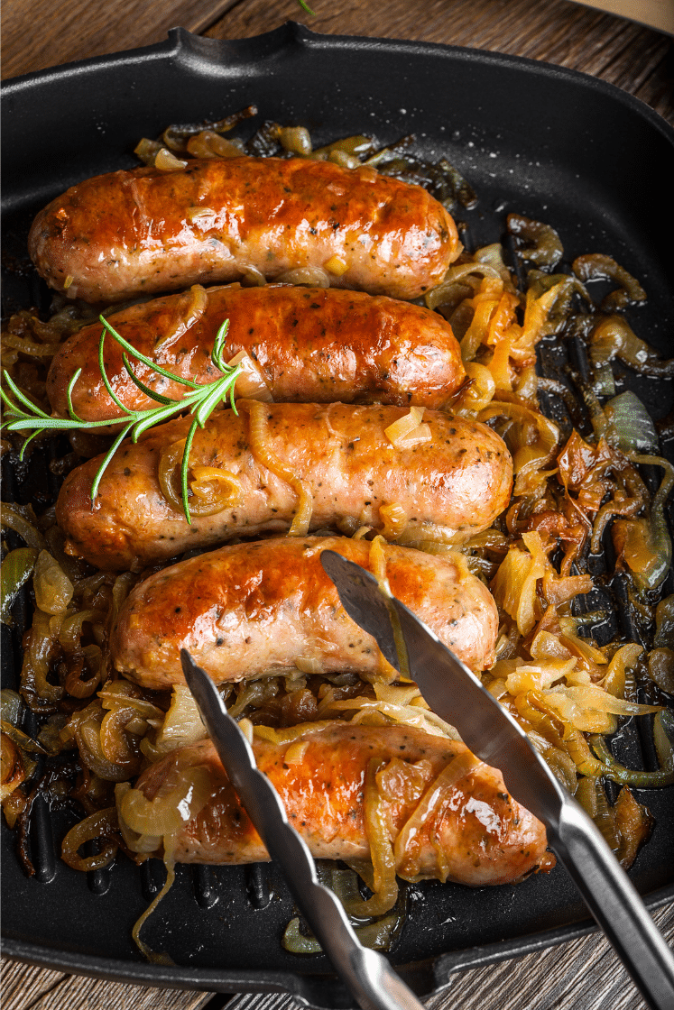 Italian sausages sauteed with onions on a grill pan.