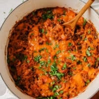 Garnished stuffed bell pepper casserole with a wooden spoon in a pot.