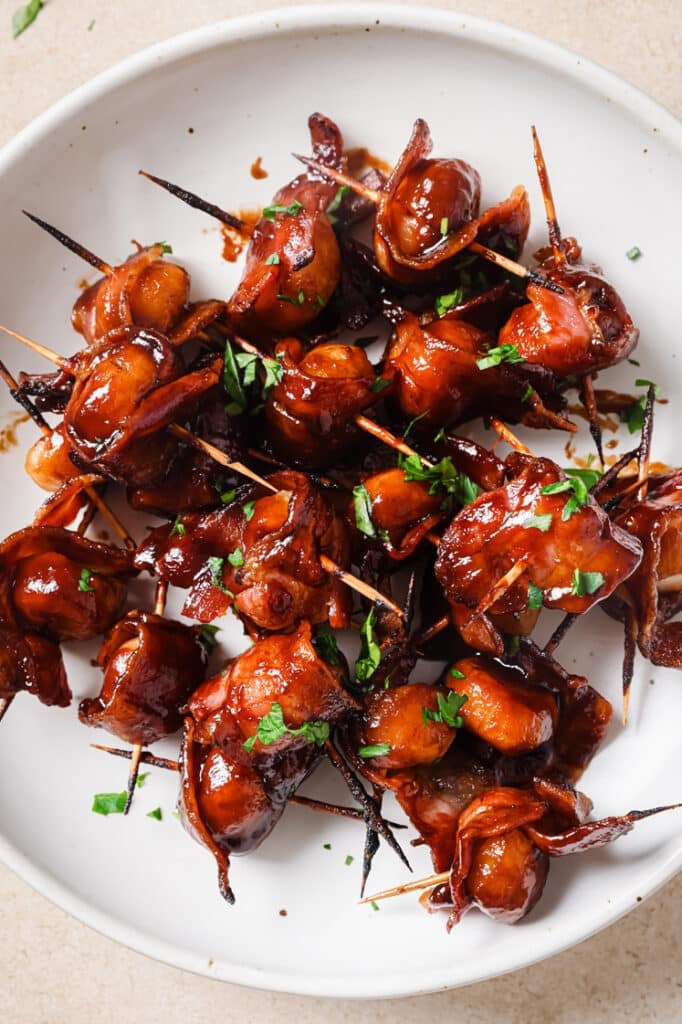 A plate of garnished bacon-wrapped water chestnuts.