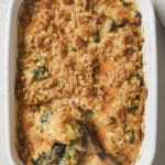 Broccoli casserole with a wooden spoon on a baking dish.