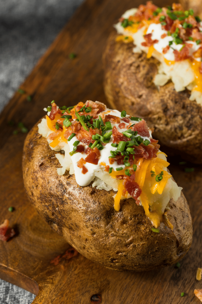 Baked potatoes with toppings on a wooden board.