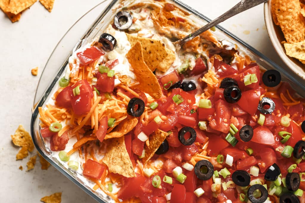 A dish of dip with tomatoes, olives, and black olives.