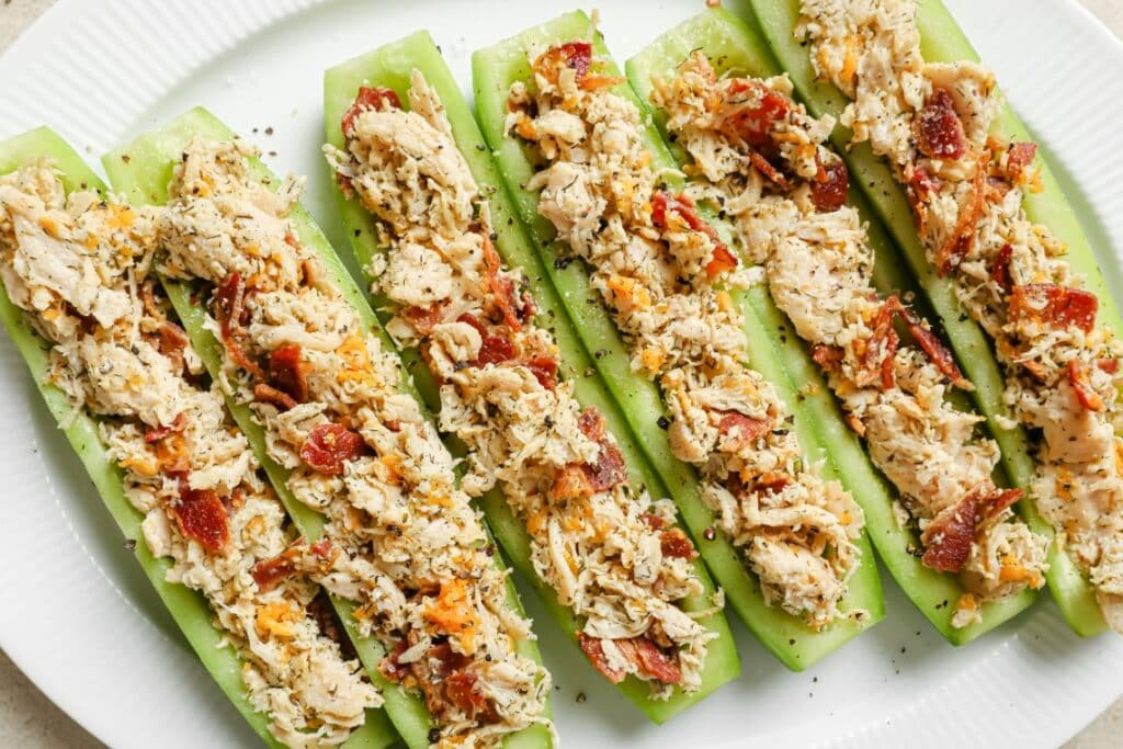 Stuffed celery sticks with chicken and bacon on a white plate.