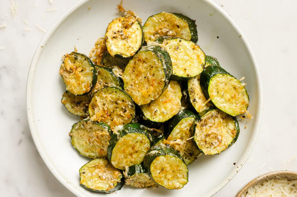 Grilled zucchini with parmesan on a white plate.