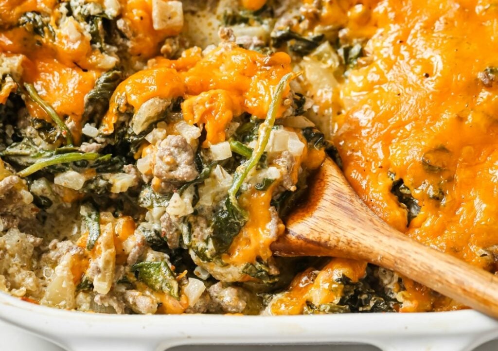 A casserole dish with meat and spinach in it.
