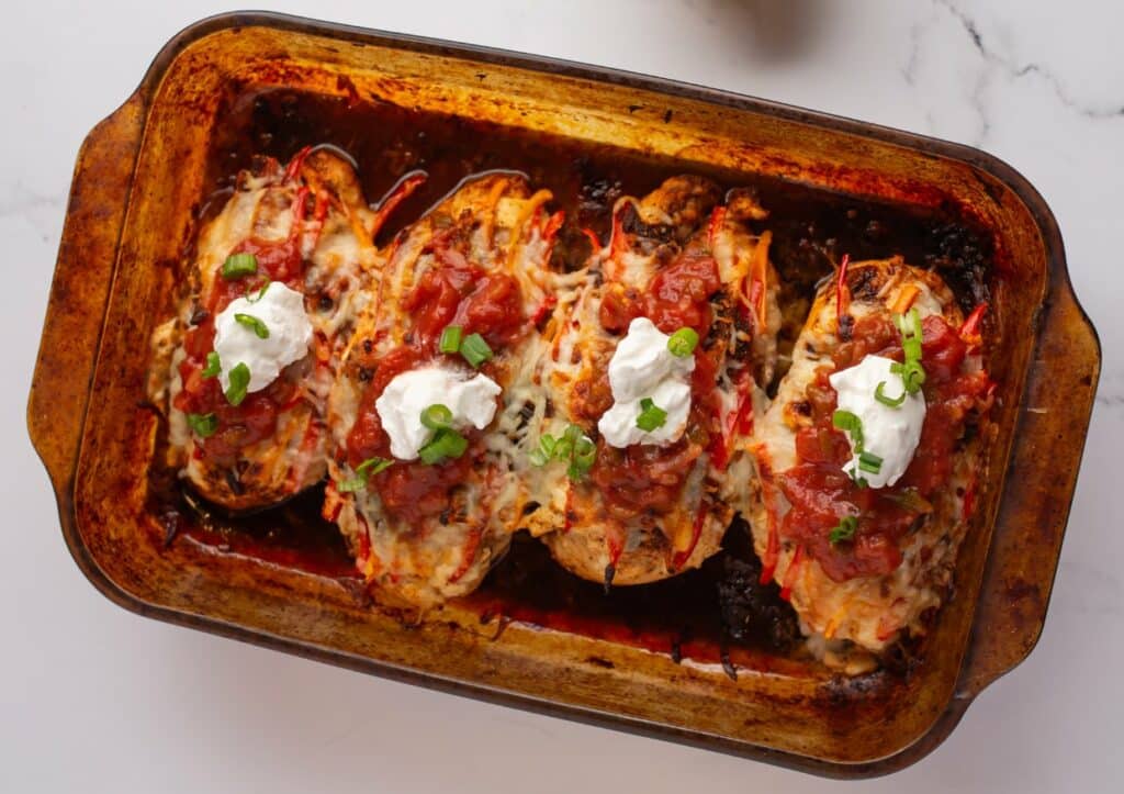 Mexican stuffed peppers in a baking dish with sour cream.