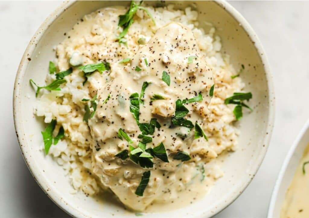 Creamy garlic chicken in a bowl garnished with herbs.