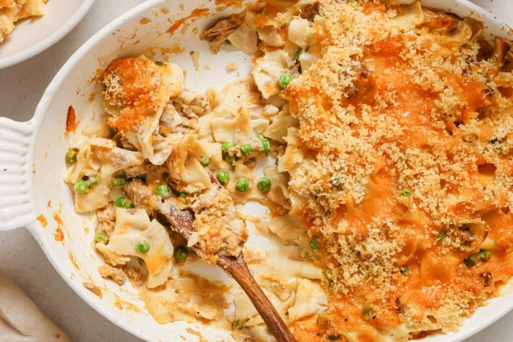 Baked casserole dish with chicken, peas, and a breadcrumb topping on a table.