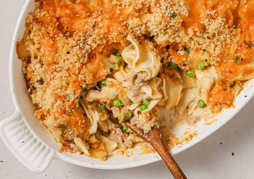 A casserole dish filled with tuna, pasta, and peas.