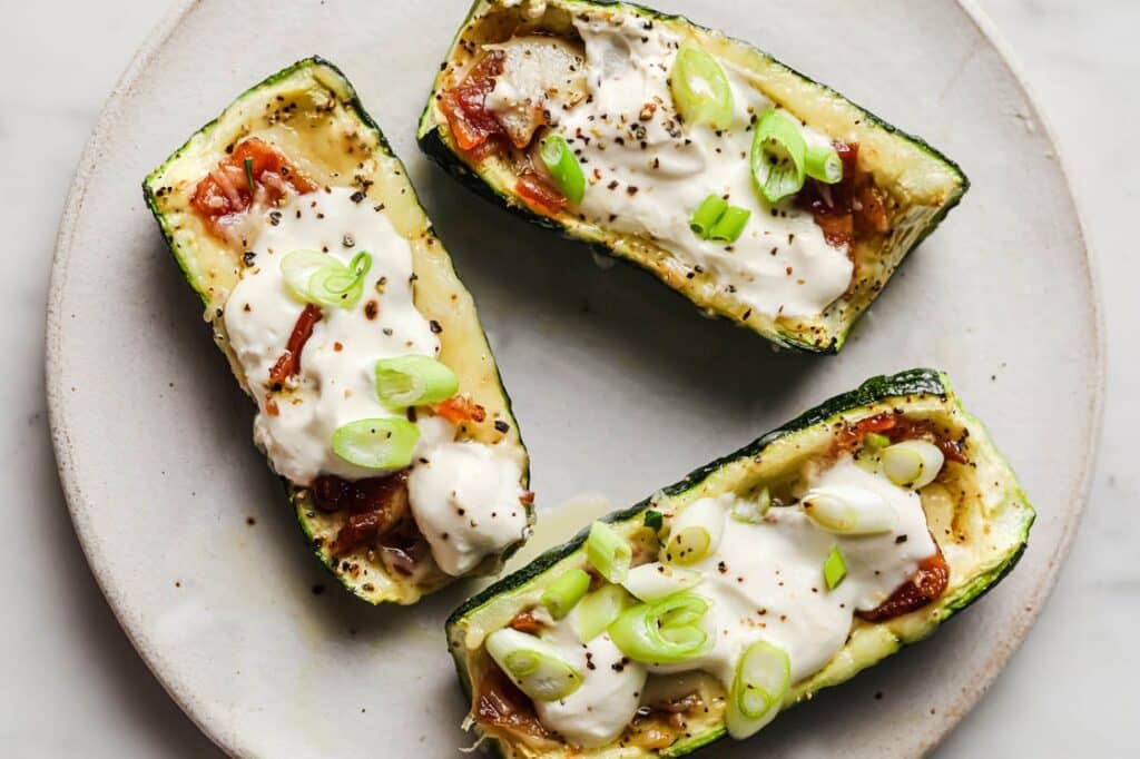 Three loaded zucchini boats on a plate.
