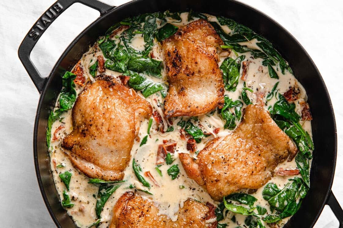 Chicken with spinach and cream sauce in a skillet.