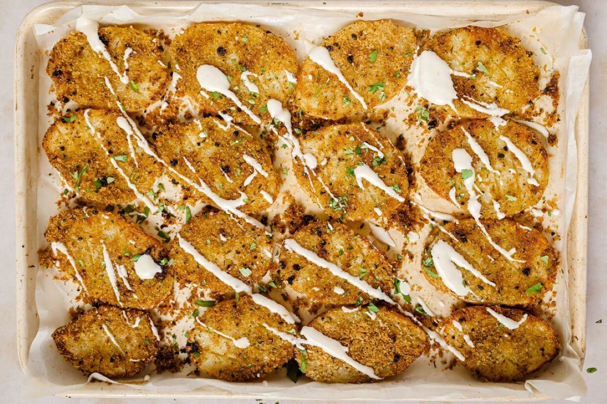 A baking sheet with garnished parmesan crusted potatoes on it.