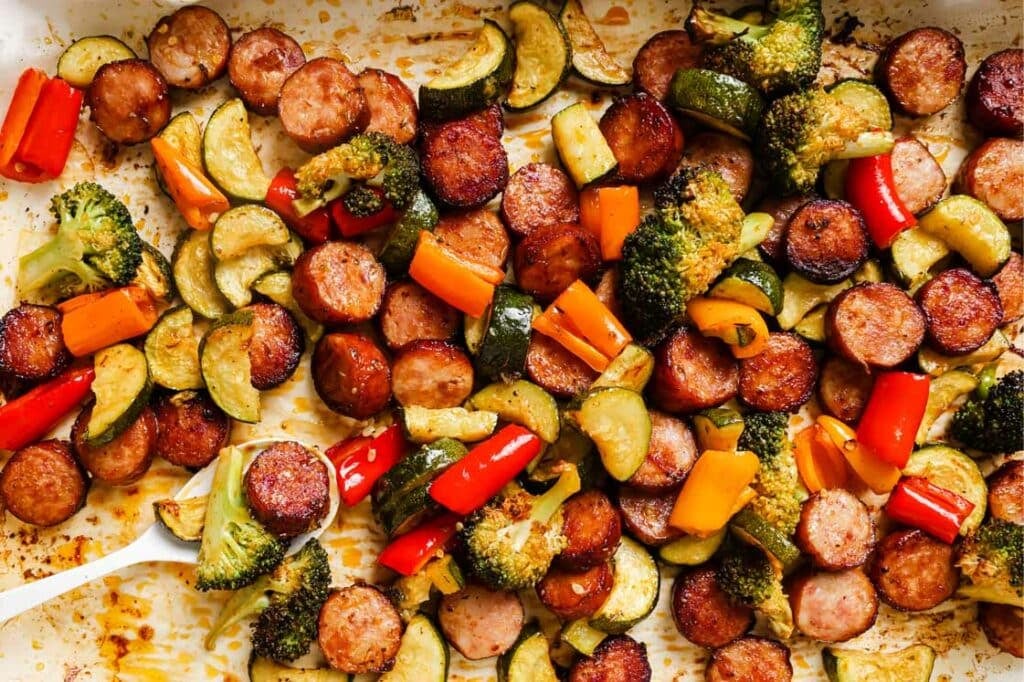 A baking sheet filled with vegetables and sausages.