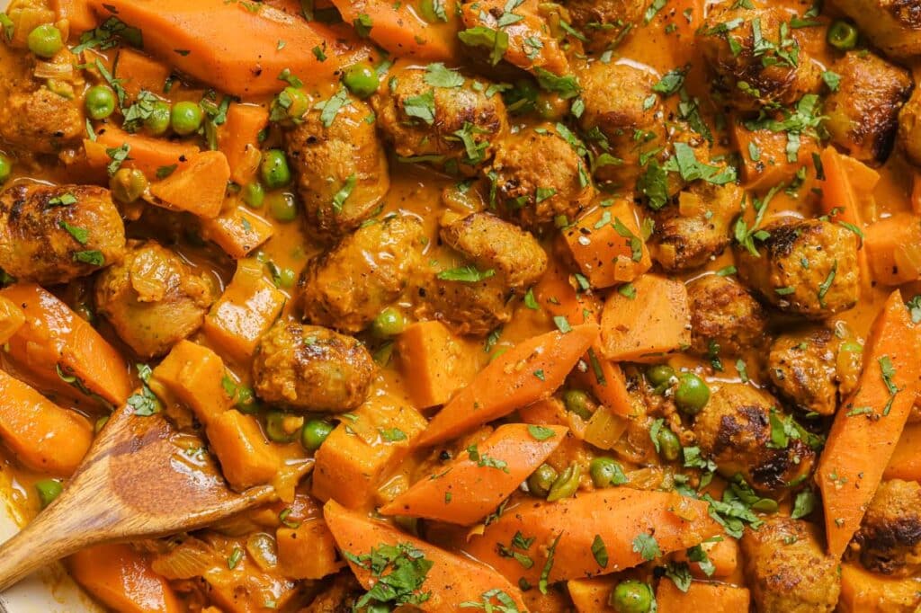 A dish with meat, carrots and peas in it.