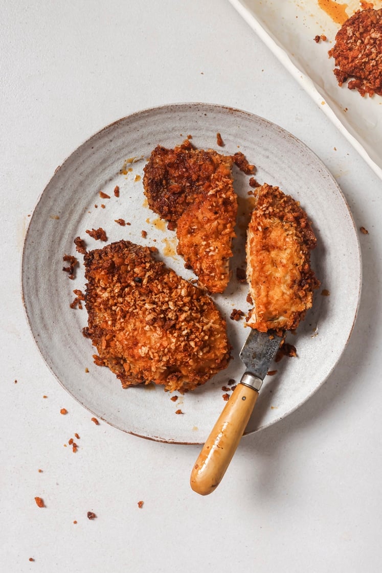 Shake and bake pork chops on a plate with a knife.