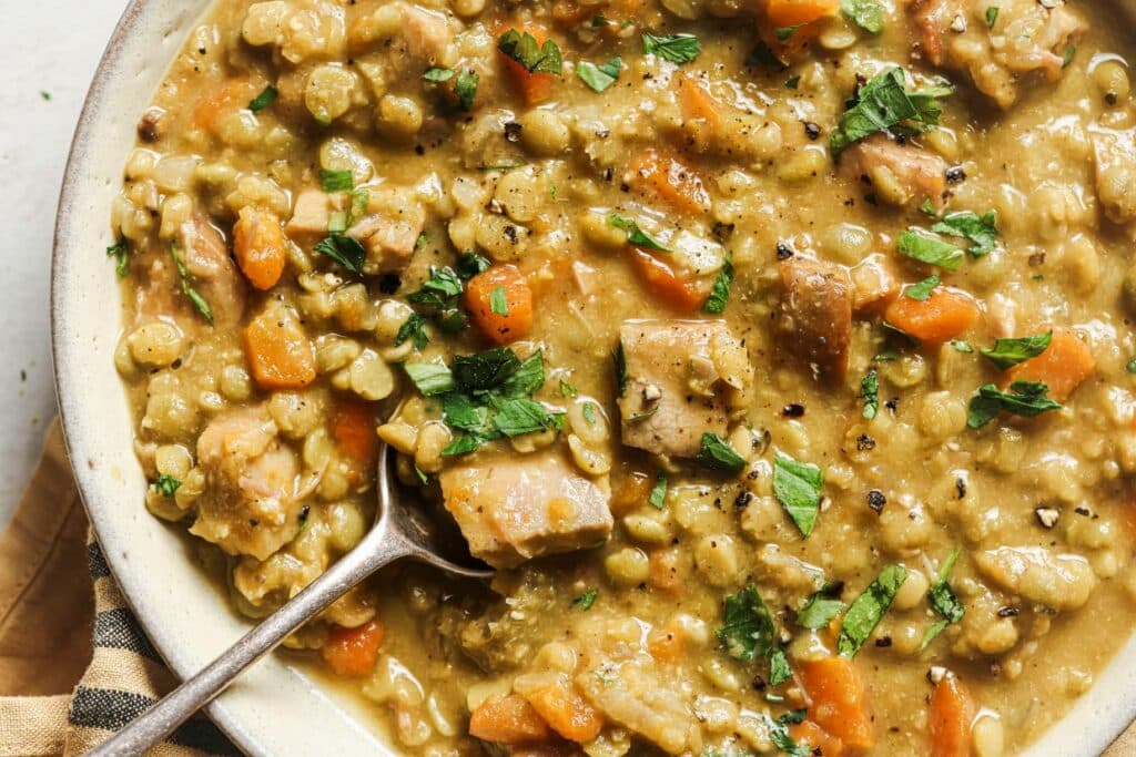 Slow cooker split pea soup in a bowl with a spoon.