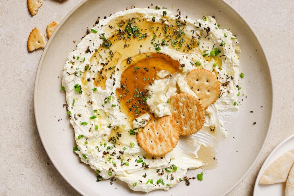 A plate of food with crackers and a dip.