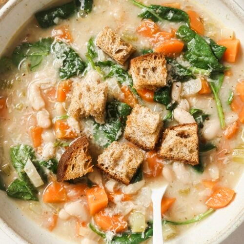 White bean soup with croutons in a bowl with a spoon.