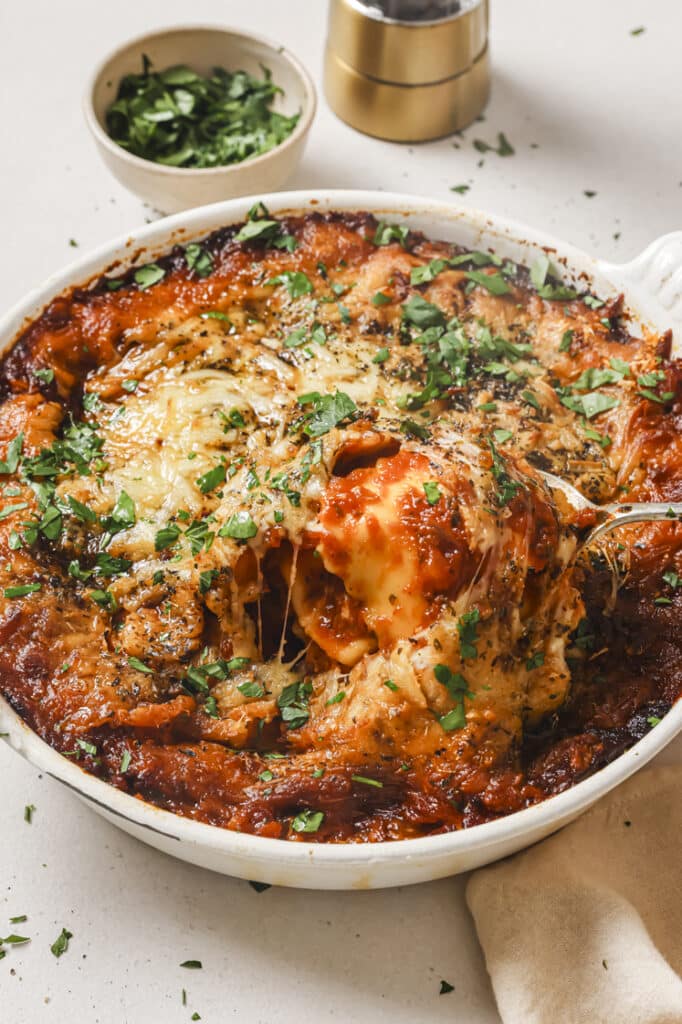 Baked ravioli in a baking dish, scooped with a spoon.