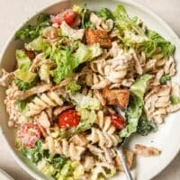 Chicken Caesar pasta salad on a plate with a spoon.