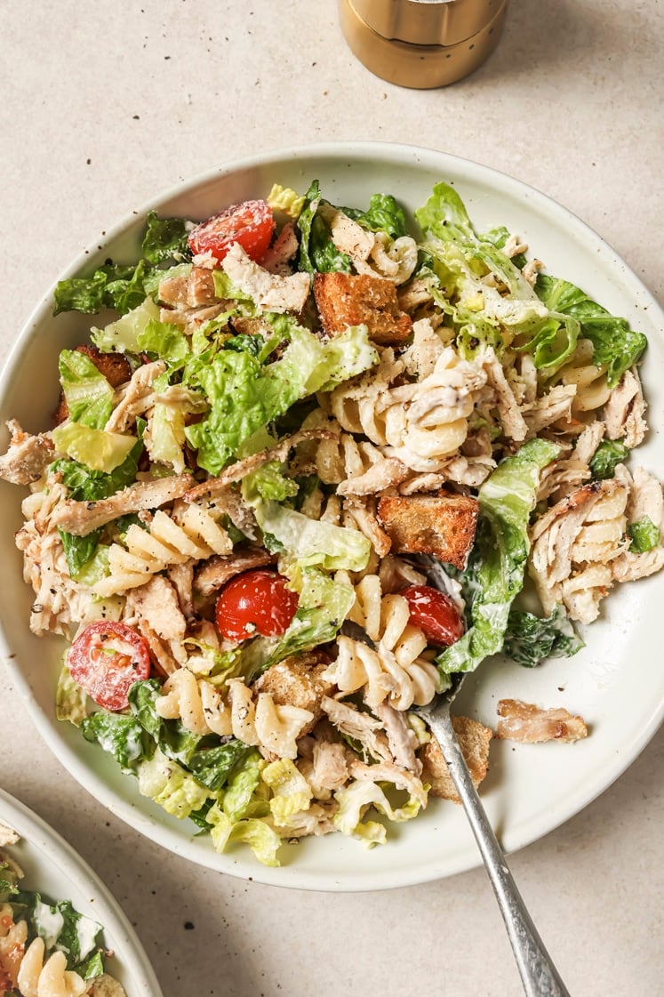 Chicken Caesar pasta salad on a plate with a spoon.