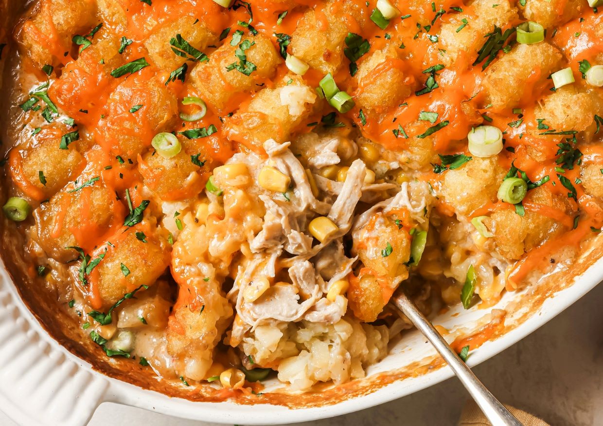 Chicken tater tot casserole with a spoon in a casserole dish ready to be served.