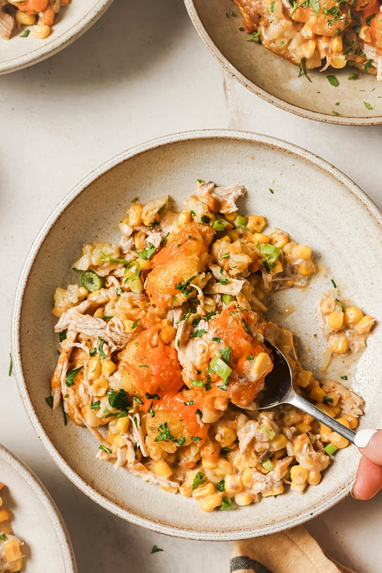 Chicken tater tot casserole being scooped out with a spoon on a plate.