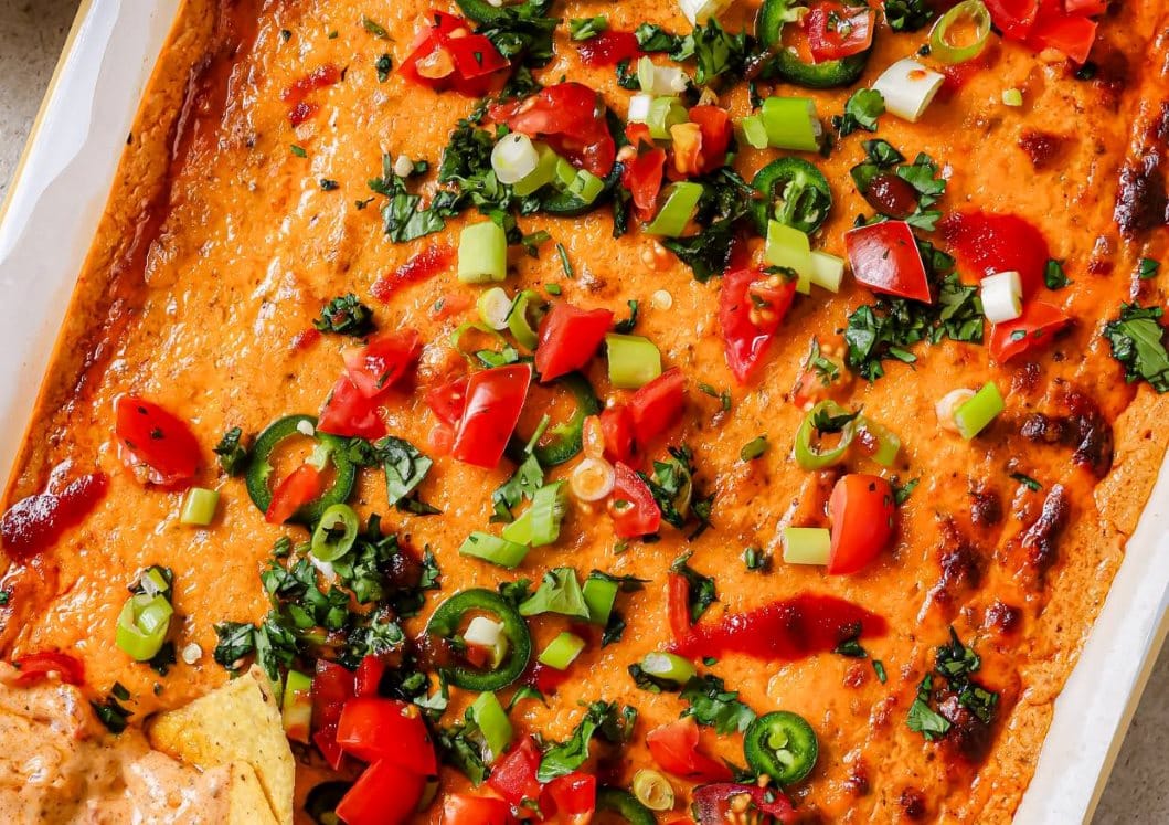 Chili cheese dip in a baking dish with toppings.