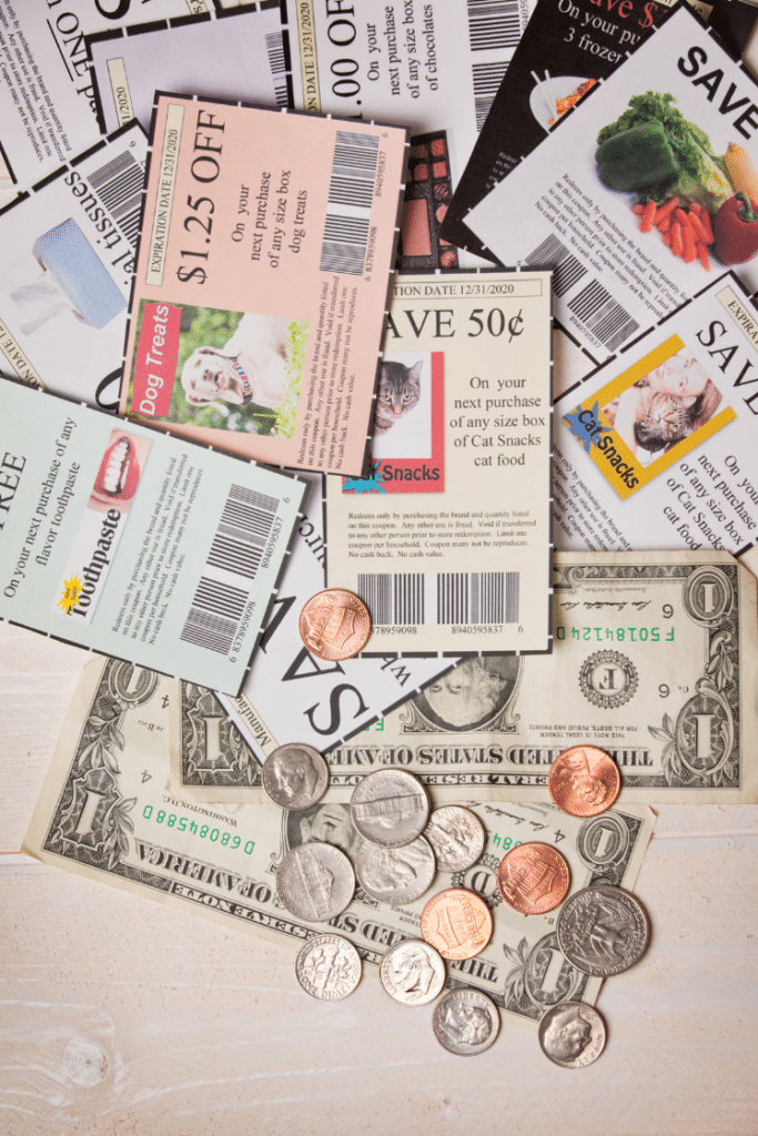 Coupons and rewards with dollar bills and coins on a table.