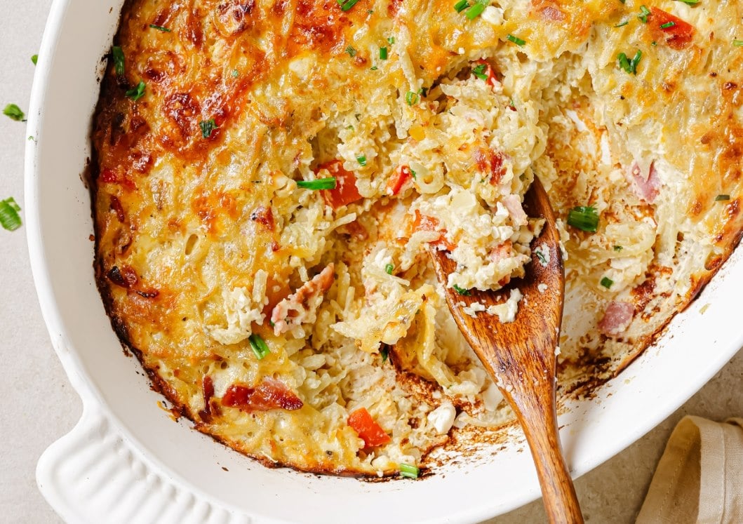 Hash brown breakfast casserole with a wooden spoon in it.