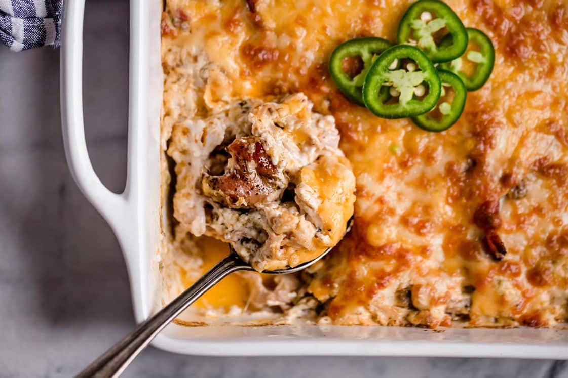 A spoon scooped into a dish of jalapeño popper chicken casserole.