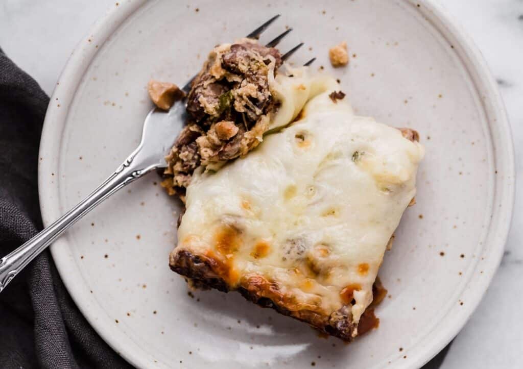 A slice of Philly cheese steak casserole on a plate with a fork.