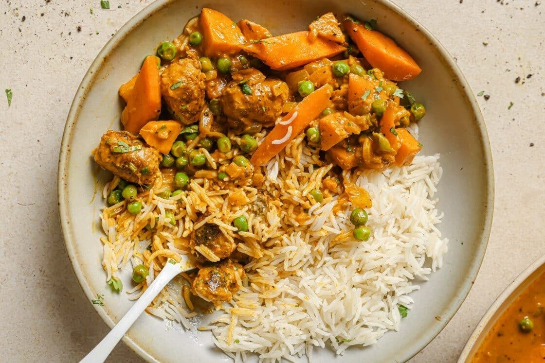 Sausage curry in a skillet garnished with herbs.