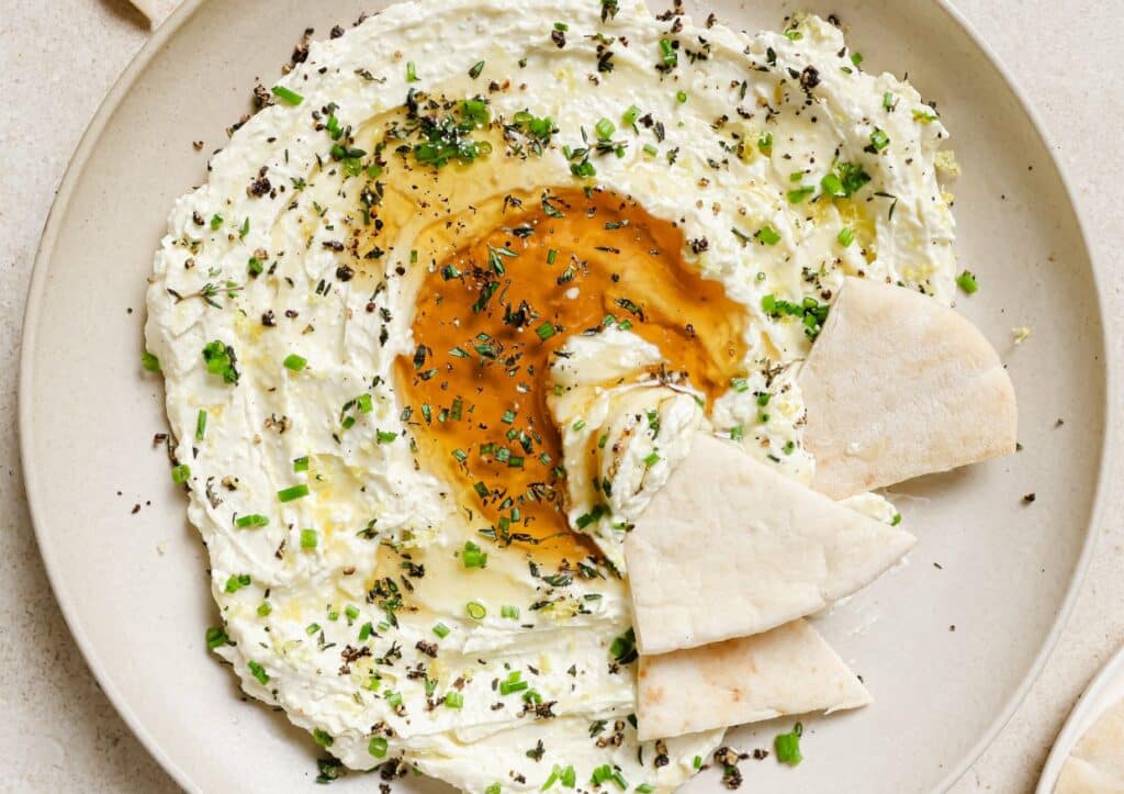 A plate of whipped feta with honey dip with pita slices.