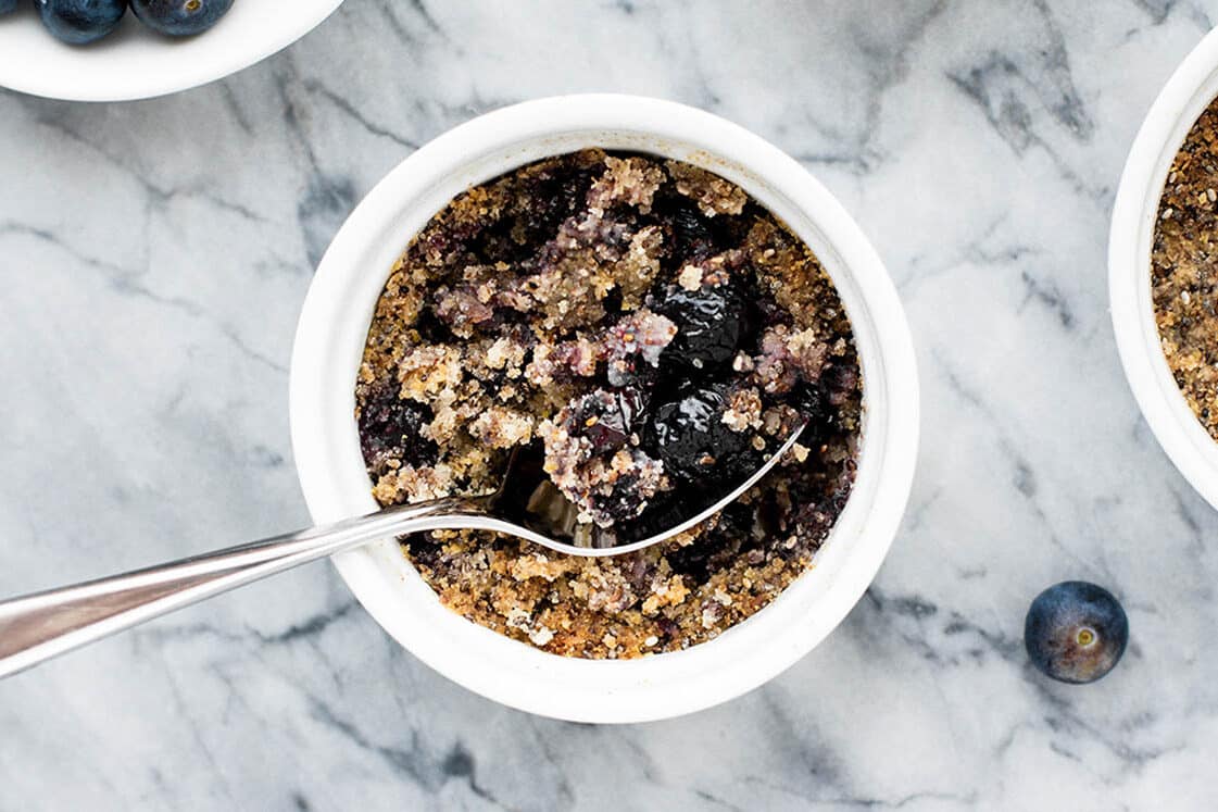 Blueberry crumble in a ramekin with a spoon.