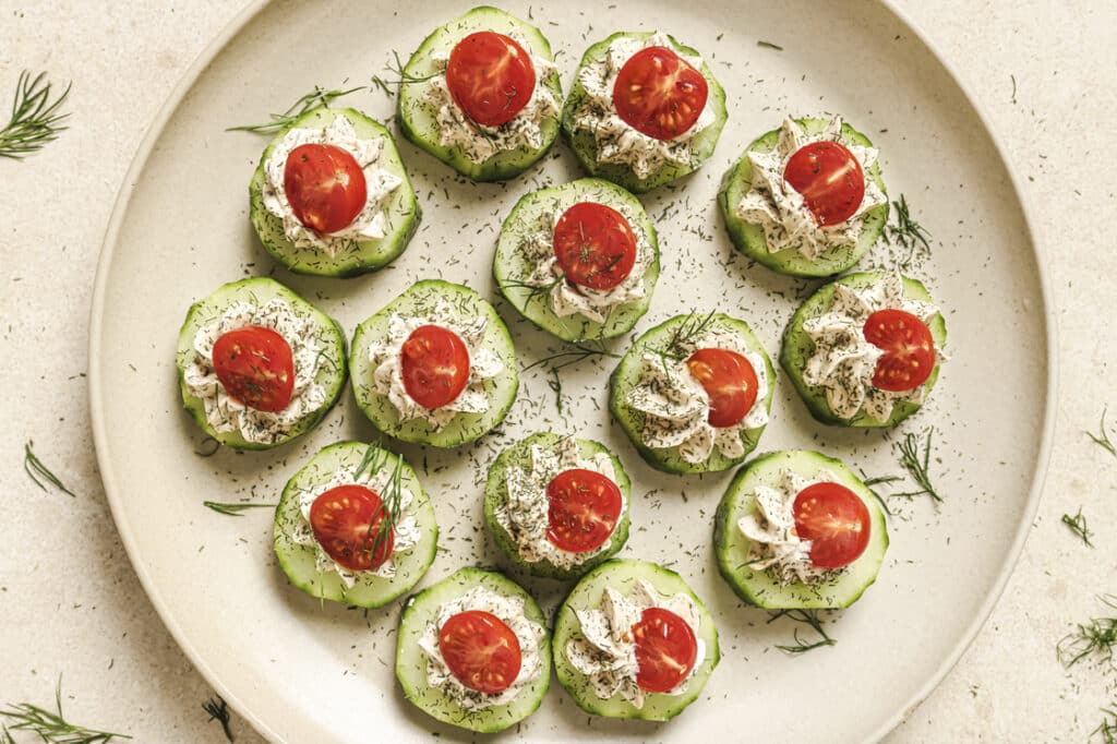 Garnished cucumber tomato bites on a plate.