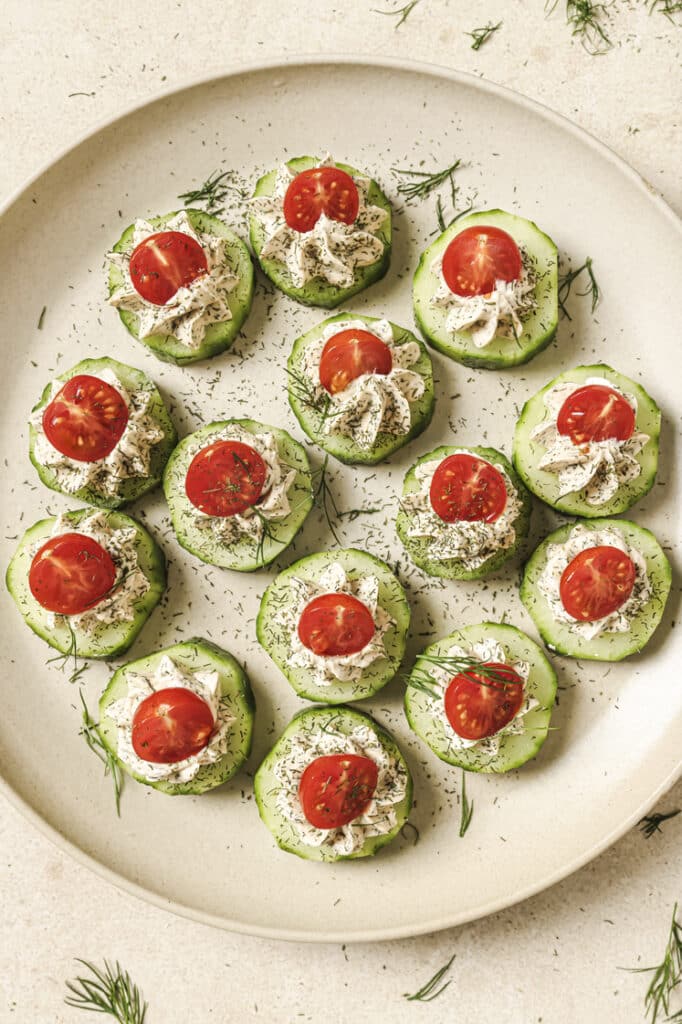 Garnished cucumber tomato bites on a plate.