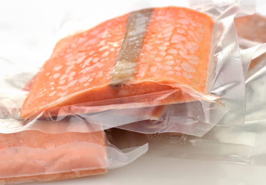 Multiple frozen salmon filets vacuum-sealed.