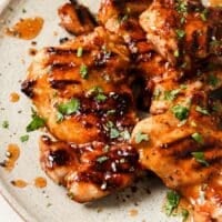 Garnished grilled hot honey chicken on a plate.