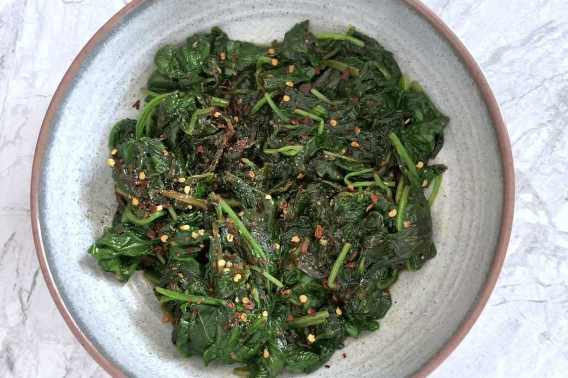 Garnished lemon garlic spinach on a plate.