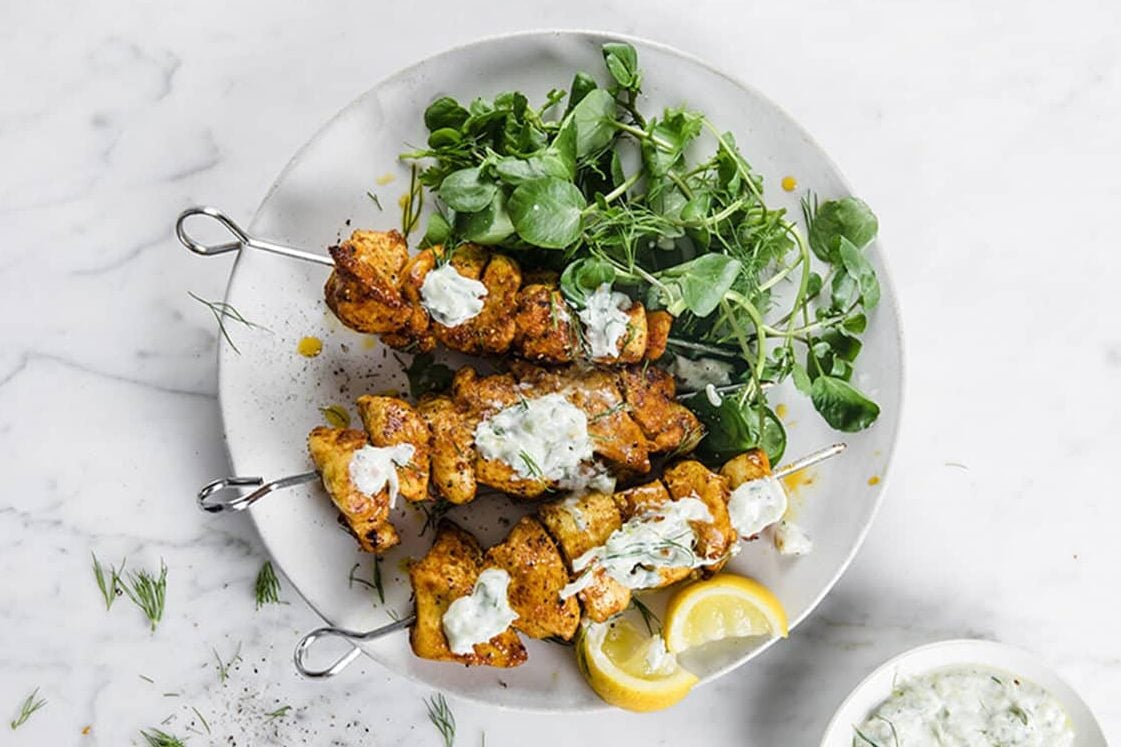 A plate of shawarma kebabs with greens and lemon slices.