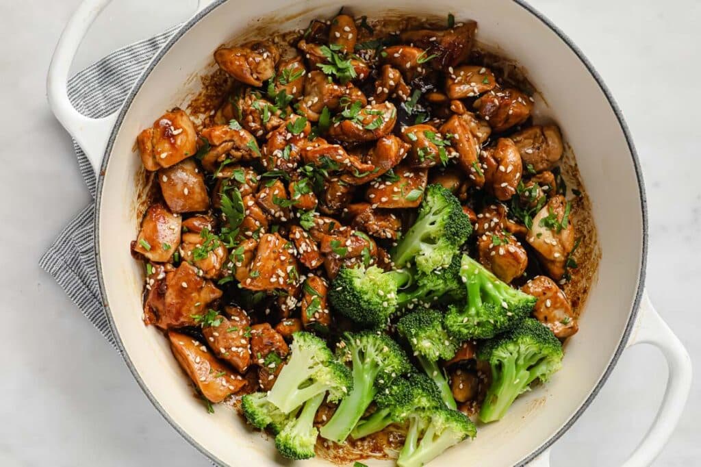 Sticky sauce chicken with broccoli florets on a pan.