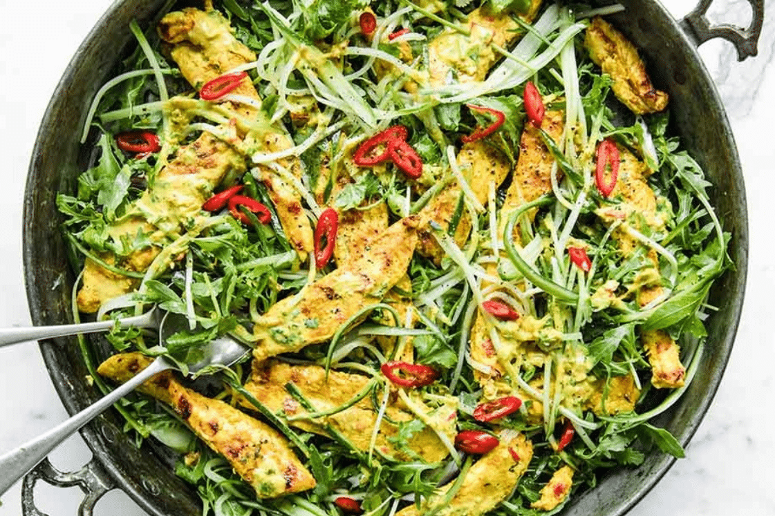 Thai chicken salad with arugula, sliced onions, and red chili peppers.